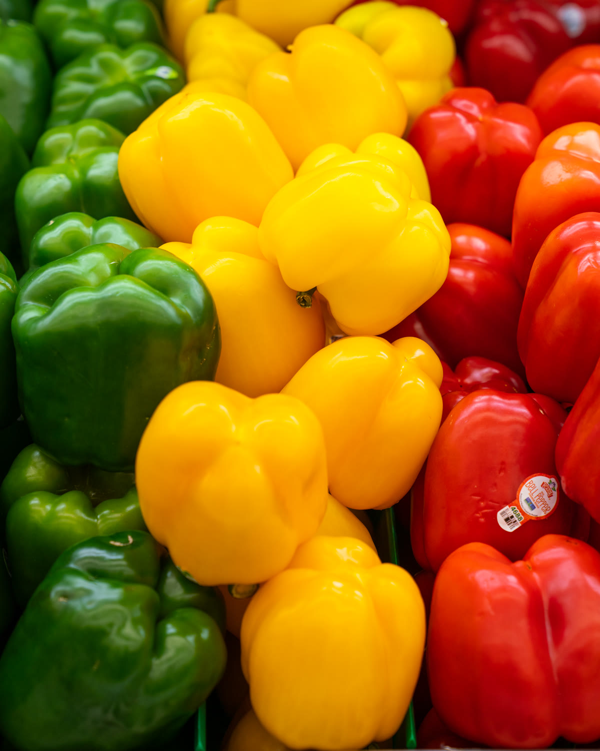 Green, yellow, and red bell peppers piled high in the produce section