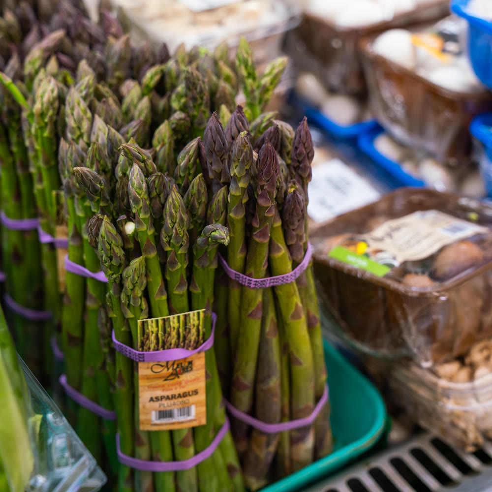 Bundles of fresh green and purple asparagus standing upright