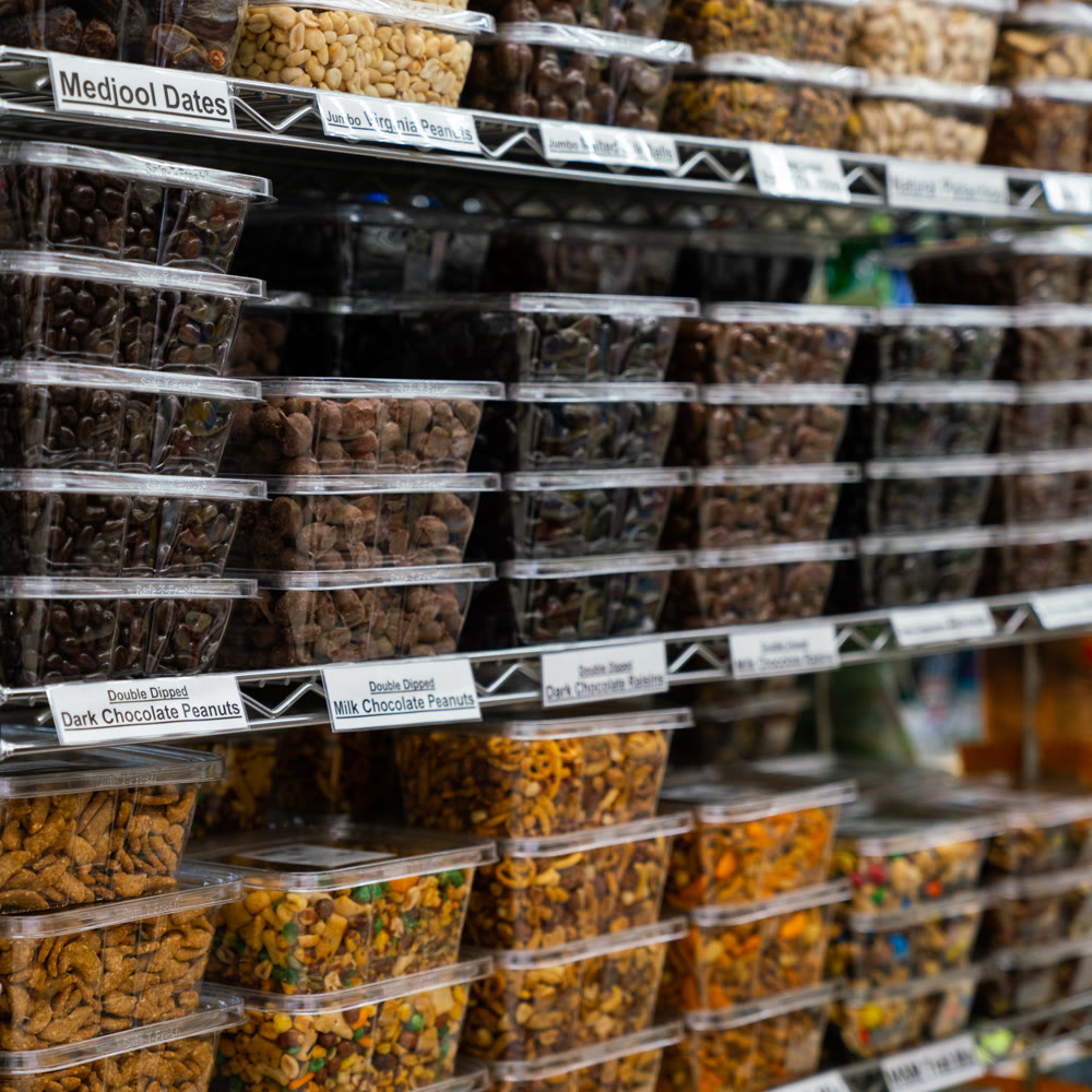 Shelves of tubs filled with dates, chocolate peanuts, and snack mixes